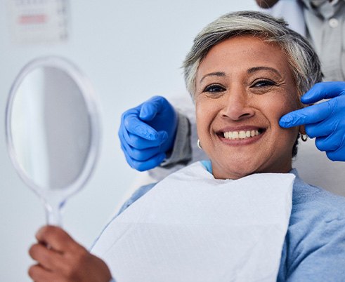Woman smiling while holding small mirror