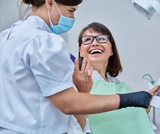Woman smiling with dentist while reviewing X-ray
