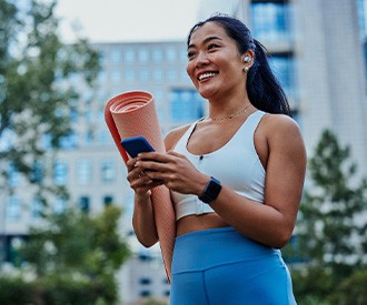 Smiling woman with yoga mat walking in park