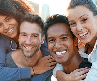 Four adults outside smiling together in the sun