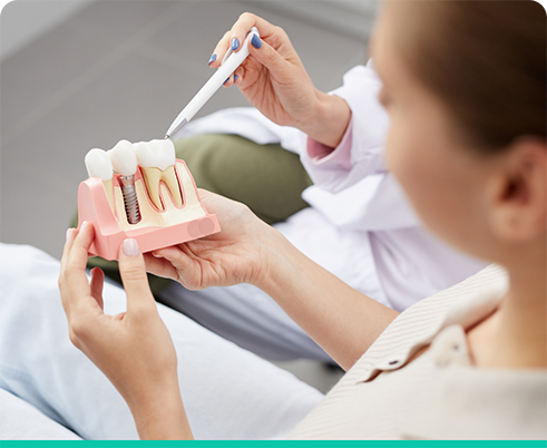 Dental patient holding model of dental implant in Houston