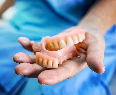Dentist in Houston holding a few dentures 