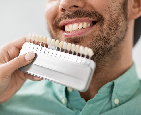 Dentist holding shade scale to patient's teeth