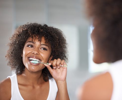 Woman smiling while brushing her teeth