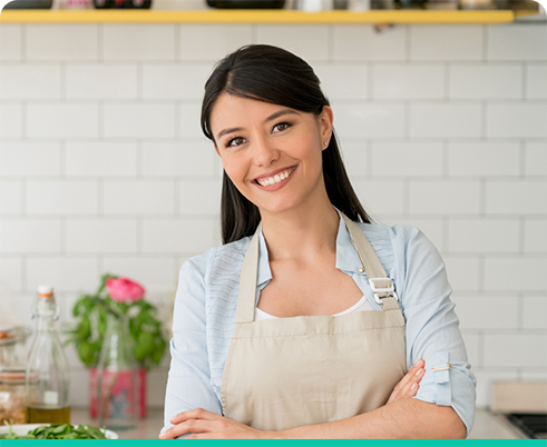 Woman with apron smiling with arms folded in Houston