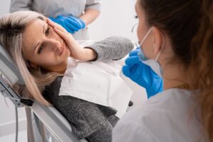 Woman holding her jaw in pain in the dentist's chair.