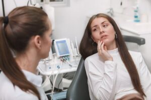 Woman telling her dentist about her lingering tooth sensitivity